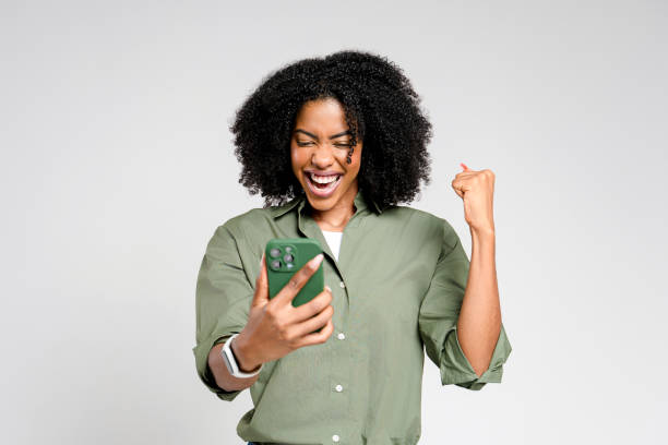 istock An ecstatic African-American woman celebrates while looking at her smartphone 2147543470