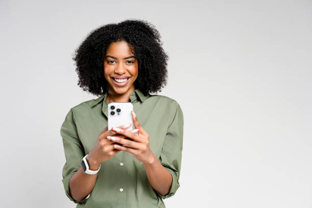 istock A radiant African-American woman smiles while using her smartphone 2147543471