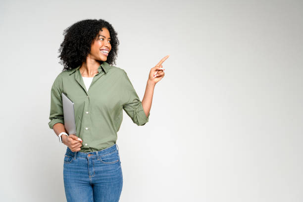 istock Smiling broadly, this African-American woman holds a tablet and points to an empty space 2147543484