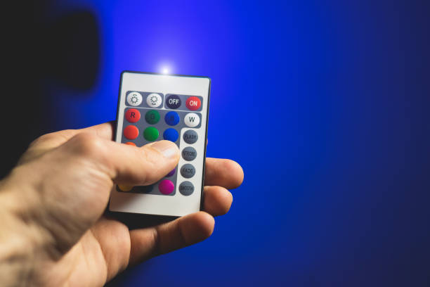 istock Man is adjusting Atmosphere Neon Light with Remote Control and turn on blue colour. Colorful RGB Bulb. LED Multicolor Lump. Household Lighting. Blogging and business modern cool lighting. 2147543508
