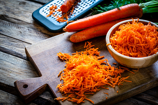 Fresh organic shredded carrots in a wooden bowl. High resolution 42Mp studio digital capture taken with Sony A7rII and Sony FE 90mm f2.8 macro G OSS lens