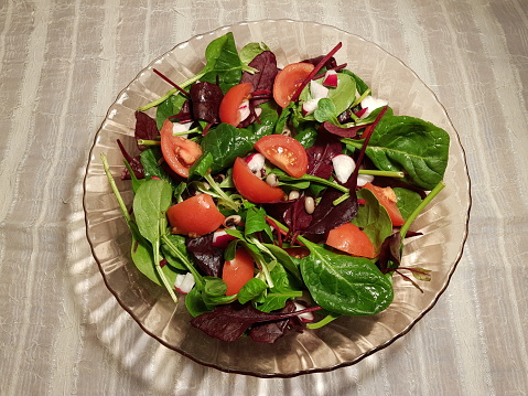 Leaf and tomato salad. Salad ingredients are black eyed beans, betroot, radish, tomato, spinach, lamb's lettuce, chard. Served in Glasgow Scotland England