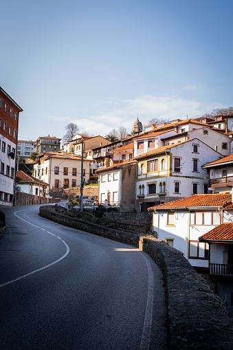 Main road cuts through Lastres village, rustic houses with warm orange rooftops.