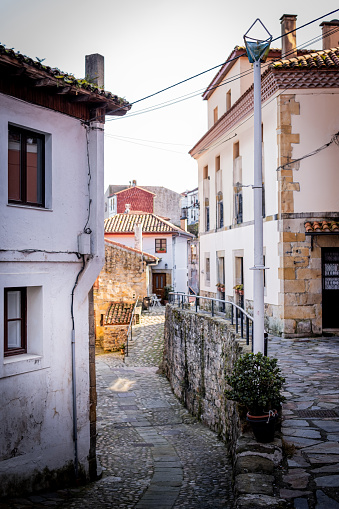 Charming village street, stone houses bathed in warm sunlight, tranquil ambiance, sunny day.