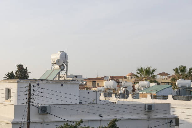 White water storage tanks on building rooftops with a clear sky in the background.