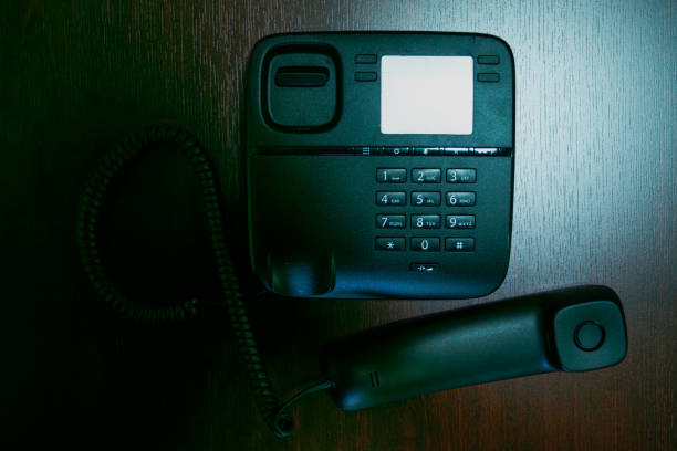 A sleek black phone and its handset rest on a desk, embodying modern communication technology in a contemporary office workspace.