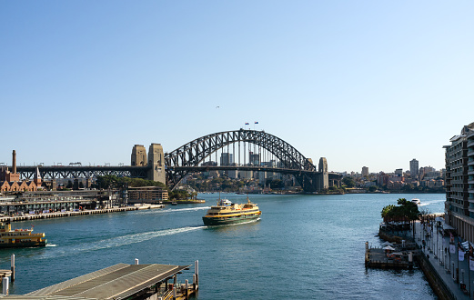 A clear morning in Sydney, New South Wales, and this is the view looking across Sydney Harbour towards the city's iconic Harbour Bridge. A ferry has just steamed out of Circular Quay ferry terminal, destination Manly.