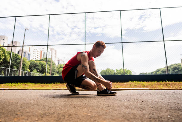 Young man tying shoes on the public park