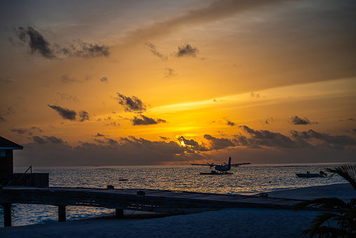 A mesmerizing sunset over the blue Maldives, with a seaplane gliding over the turquoise sea, creating an idyllic and serene island escape