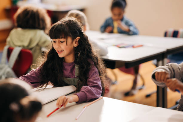 istock Female elementary school student sitting at her desk and doing her school work 2147550404