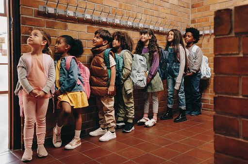 Primary school students waiting in line outside their classroom. Group of children eagerly waiting to start class in the morning. Elementary age kids standing together in school.