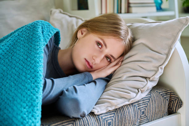 istock Relaxed young female looking at camera, lying on pillow under blanket 2147551931