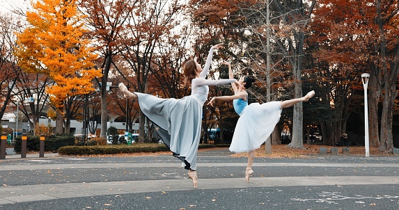 Ballet, dancing and women in autumn on the street in Japan park with pointe shoes and creative pose. Outdoor, ballerina and people with performance of talent, art and stretching legs in Kyoto