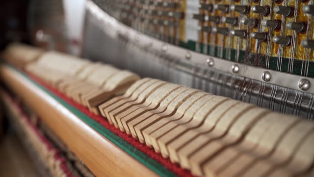 Hammers and strings inside piano, close up. Hammer in action, piano key is pressed.