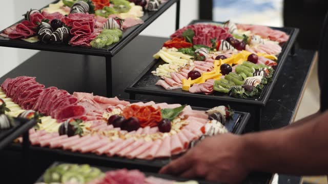 Waiter places charcuterie board at a wedding or business banquet