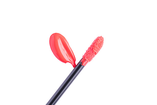 Red liquid lipstick and applicator isolated on white background. Swatch of red lip gloss. Top view, flat lay, copy space