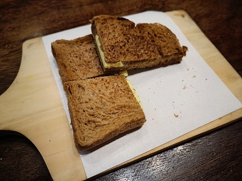 The appearance of slices of toast with a combination of srikaya butter flavor is served on a wooden coaster with a piece of tissue as a base