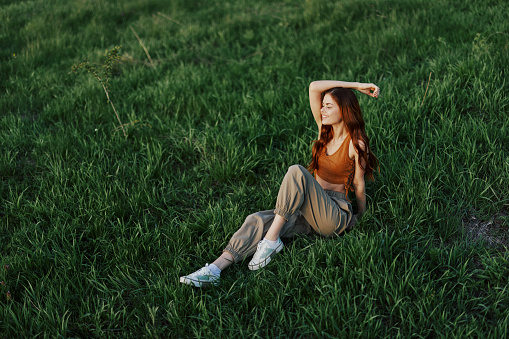 Woman sitting on green grass in nature in a park, view from above. High quality photo