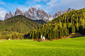 Sunny landscape with church of San Giovanni against the Geisler peaks covered with snow in Santa Maddalena village, Val Di Funes in Dolomites mountains, Trentino Alto Adige, Italy