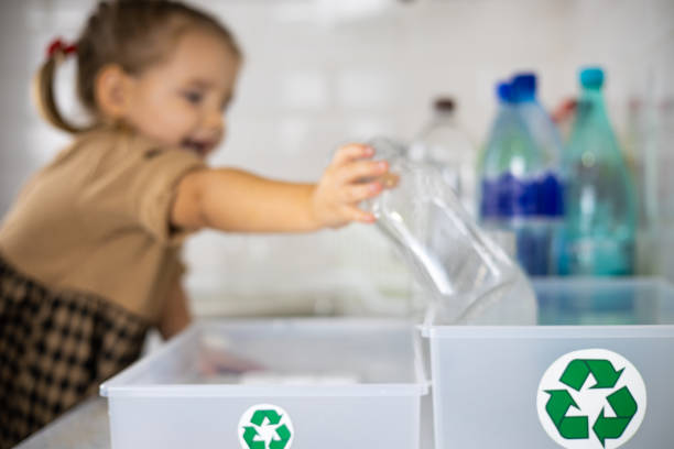 A child laughs cutely and puts plastic bottles from a box with a recycling sign. A daughter helps her mother sort plastic bottles for recycling. Planet care concept, plastic recycling. A child laughs cutely and puts plastic bottles from a box with a recycling sign. A daughter helps her mother sort plastic bottles for recycling. Planet care concept, plastic recycling.. cutely stock pictures, royalty-free photos & images