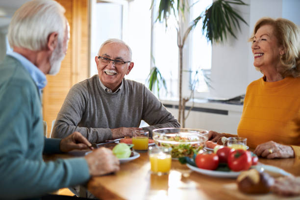 istock Group of happy senior friends talking while having a meal at dining table. 2147568090