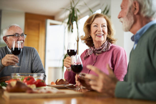 istock Happy senior friends  toasting with red wine during a meal at dining table. 2147568398