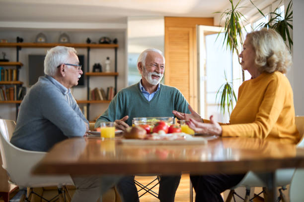 istock Group of happy senior  friends talking while having a meal at dining table. 2147568573
