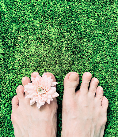 close-up of female feet with flower on towel Green background