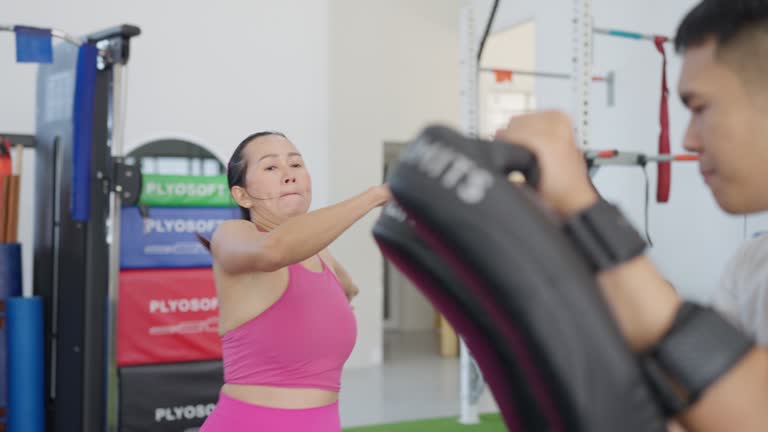 A woman is exercising in a gym with a Flyosoft sign in the background