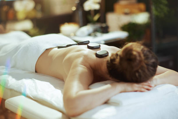 istock woman having hot stone massage and laying on massage table 2147572011