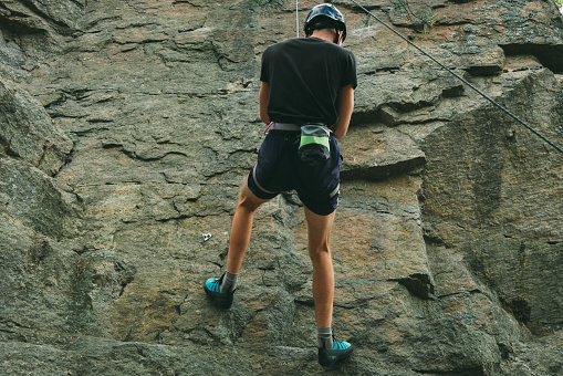 Young man in equipment doing rock climbing outdoors. Training area for outdoor activities. Extreme sport.