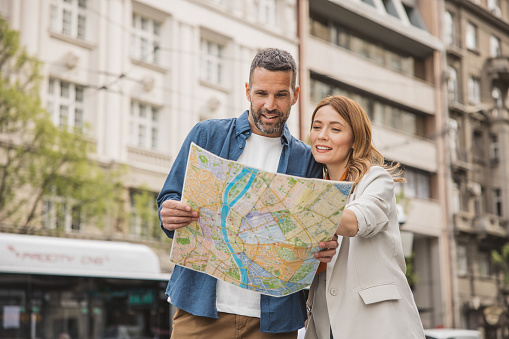 Happy couple on vacation, exploring European city. Looking map for direction.
