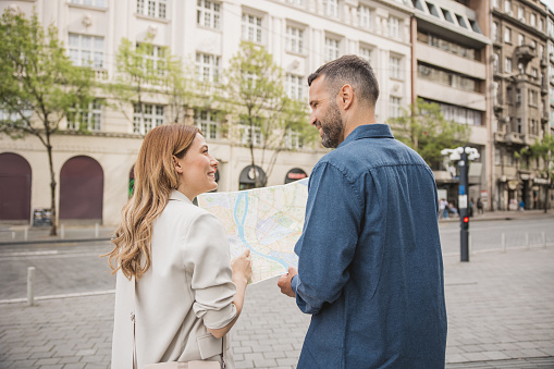 Happy couple on vacation, exploring European city. Looking map for direction.