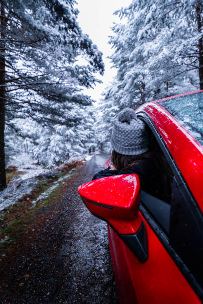 istock Snow-covered forest road frames red car, showcasing Sierra de Guadarrama scenery. 2147575900