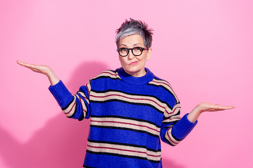 Photo of attractive pensioner woman compare skeptical empty space dressed stylish blue striped clothes isolated on pink color background.