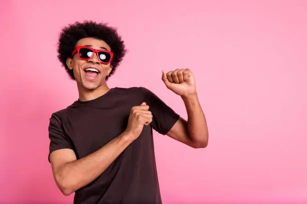 Portrait of carefree wavy hair man wear brown t shirt and sunglass rayban have fun chilling clubbing isolated on pink color background.