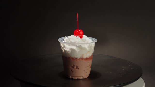 Chocolate cream cup parfait cherry on top spinning in turntable with black background