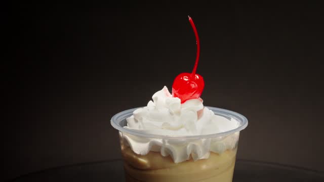 Vanilla cream cup parfait cherry on top spinning in turntable with black background copa nevada