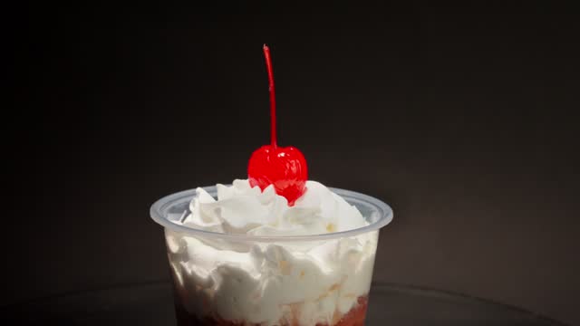 close up detail shot Chocolate cream cup parfait cherry on top spinning in turntable with black background copa nevada