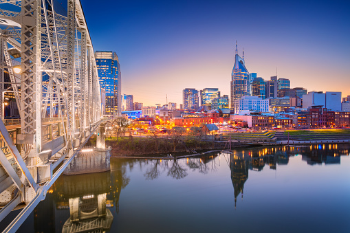 Cityscape image of Nashville, Tennessee, USA downtown skyline with reflection of the city the Cumberland River at spring sunset.