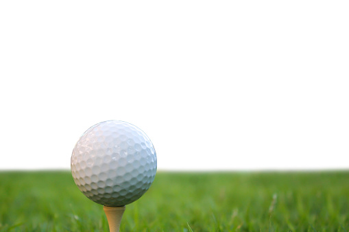 Golf ball set on golf tee on green grass, image and floor. Isolated.