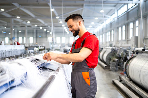 istock Textile factory worker producing carpet on industrial sewing machine. 2147582606