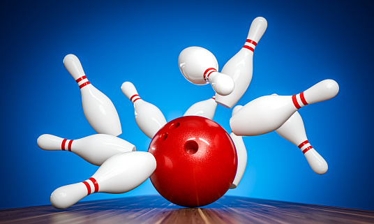 Action shot of a red bowling ball crashing into white pins against a blue backdrop. 3d render