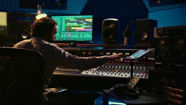 istock Sound engineer counting down for artist in vocal booth to start singing 2147583341