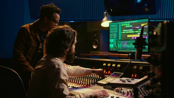 istock Team of audio technician and artist producing and editing sound on mixer console 2147584541