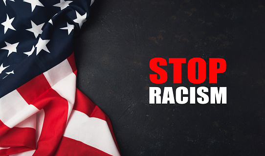 A red and white American flag with the words Stop Racism written underneath it. The flag is on a black background