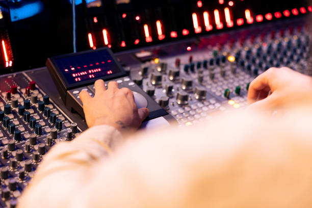 istock Tracking engineer pressing faders and buttons on control desk to balance sounds 2147585882