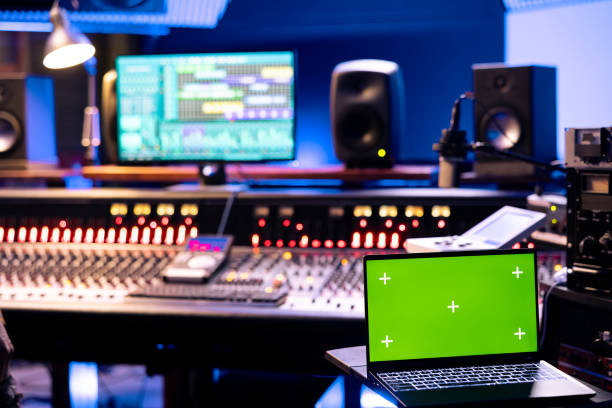 istock Young technician recording music on control desk next to mockup laptop 2147586697