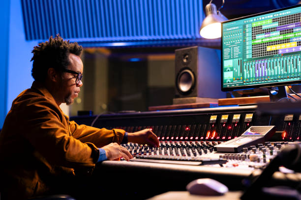 istock African american sound engineer works on mixing console with sliders and knobs 2147587361