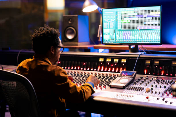 istock African american sound designer uses mixing console with knobs and faders 2147587410